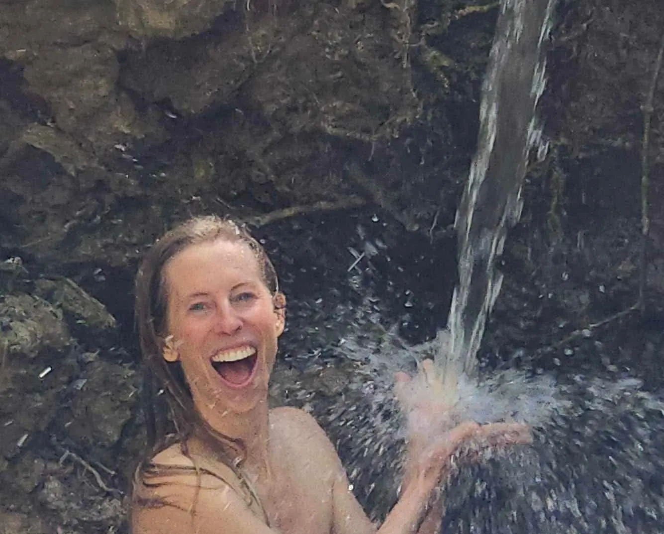 Kelci Heart laughing under a waterfall